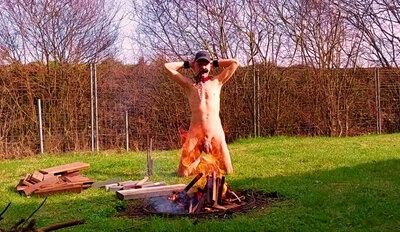 totally naked gay slave slut exposed in penis cage outdoor starting campfire for party BDSM